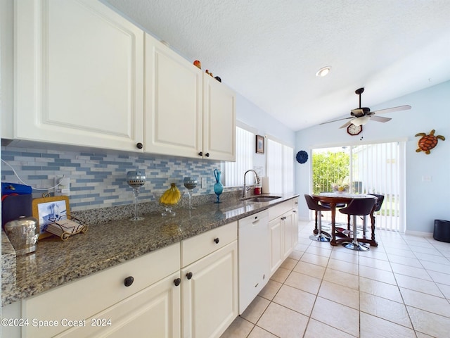 kitchen featuring white dishwasher, sink, white cabinetry, and vaulted ceiling