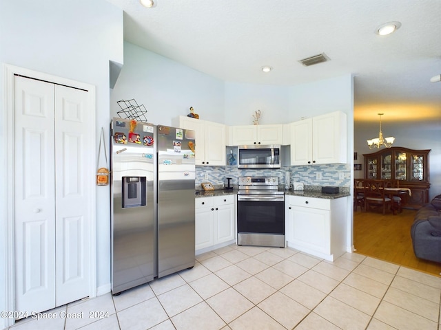 kitchen with white cabinets, a chandelier, stainless steel appliances, light wood-type flooring, and decorative backsplash