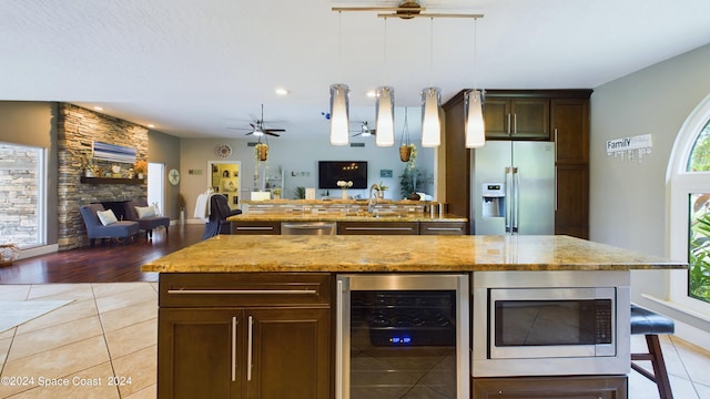 kitchen featuring light wood-type flooring, stainless steel appliances, wine cooler, ceiling fan, and hanging light fixtures