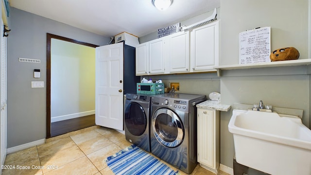 laundry room with light tile patterned floors, cabinets, sink, and washer and clothes dryer