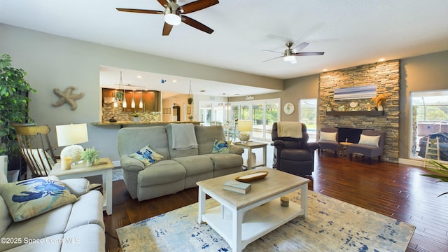 living room with a stone fireplace, recessed lighting, a ceiling fan, and wood finished floors