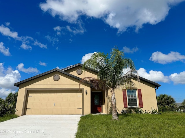 single story home featuring a front lawn, driveway, an attached garage, and stucco siding