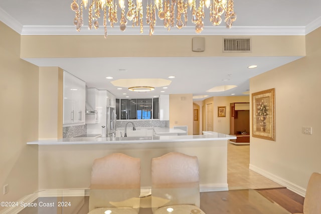 kitchen with white cabinets, stainless steel fridge, crown molding, and tasteful backsplash