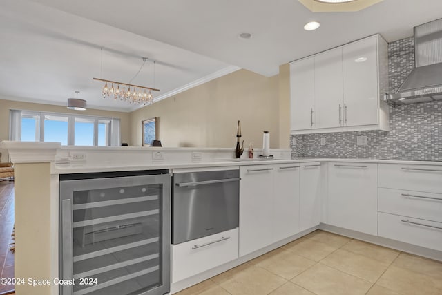 kitchen featuring tasteful backsplash, wine cooler, kitchen peninsula, wall chimney exhaust hood, and white cabinets