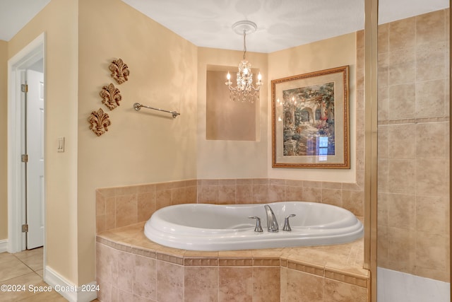 bathroom with tile patterned flooring, tiled tub, and an inviting chandelier