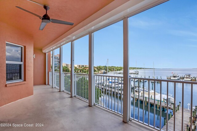 unfurnished sunroom featuring a water view and ceiling fan