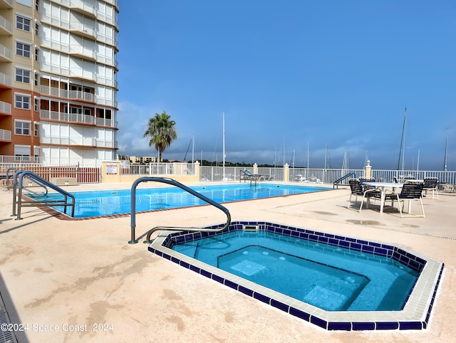 view of pool with a patio and a hot tub