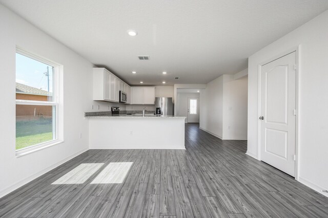 kitchen featuring appliances with stainless steel finishes, kitchen peninsula, white cabinets, and a wealth of natural light