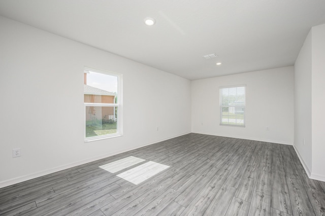 unfurnished room with a healthy amount of sunlight, baseboards, wood finished floors, and recessed lighting