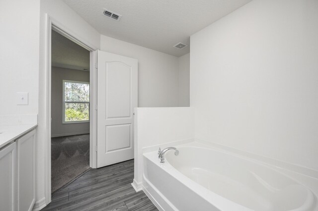 bathroom featuring vanity, a textured ceiling, hardwood / wood-style flooring, and a bathing tub