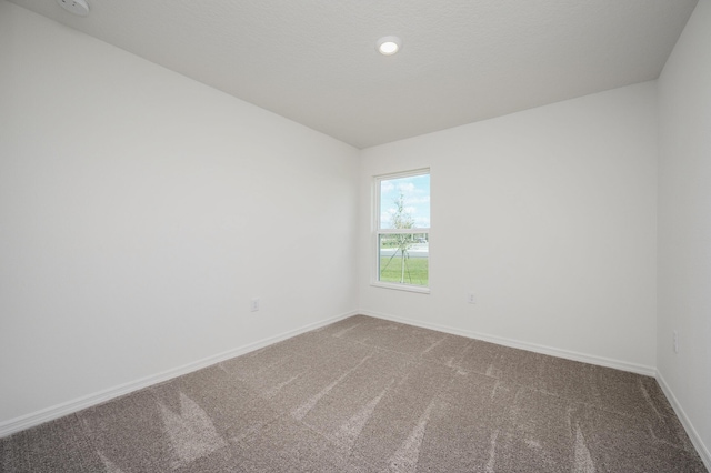 carpeted empty room featuring baseboards