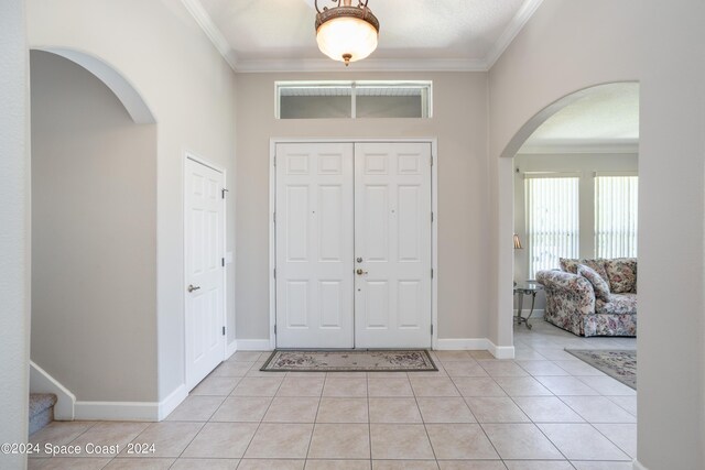 foyer featuring crown molding and light tile patterned floors