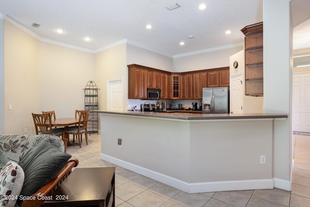 kitchen with crown molding, kitchen peninsula, light tile patterned floors, and appliances with stainless steel finishes