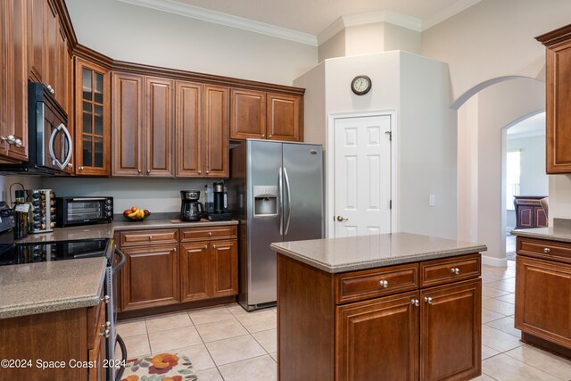 kitchen featuring crown molding, a center island, light tile patterned floors, and appliances with stainless steel finishes