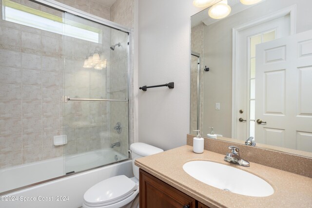 full bathroom featuring shower / bath combination with glass door, plenty of natural light, toilet, and vanity