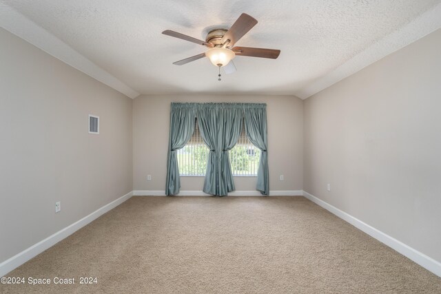 carpeted empty room featuring a textured ceiling, ceiling fan, and vaulted ceiling