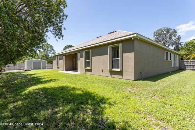 back of house featuring a yard and a storage unit