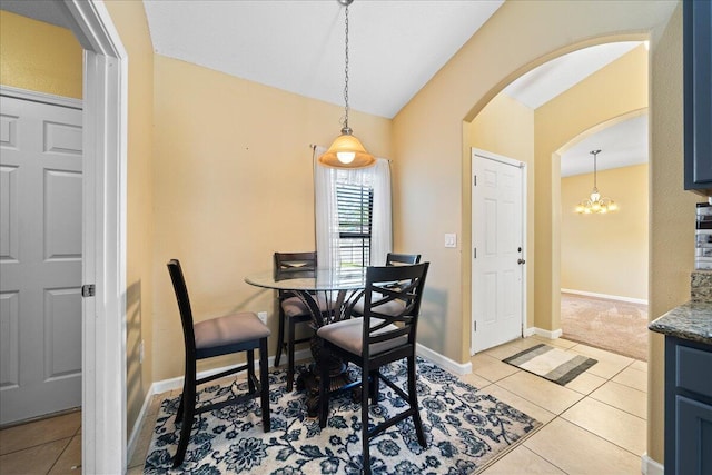 dining room with baseboards, vaulted ceiling, an inviting chandelier, light tile patterned flooring, and arched walkways