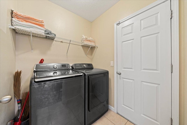 washroom with independent washer and dryer, a textured ceiling, light tile patterned floors, baseboards, and laundry area