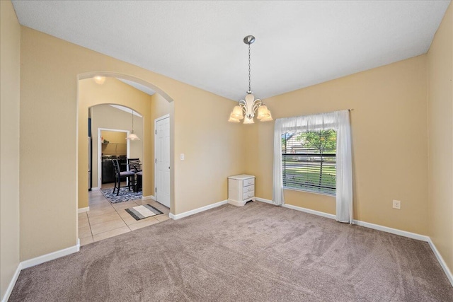 tiled spare room with arched walkways, a chandelier, baseboards, and carpet