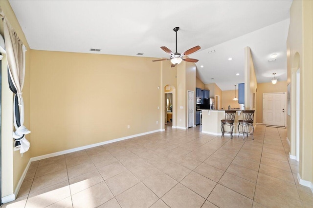 unfurnished living room featuring arched walkways, light tile patterned floors, baseboards, and a ceiling fan