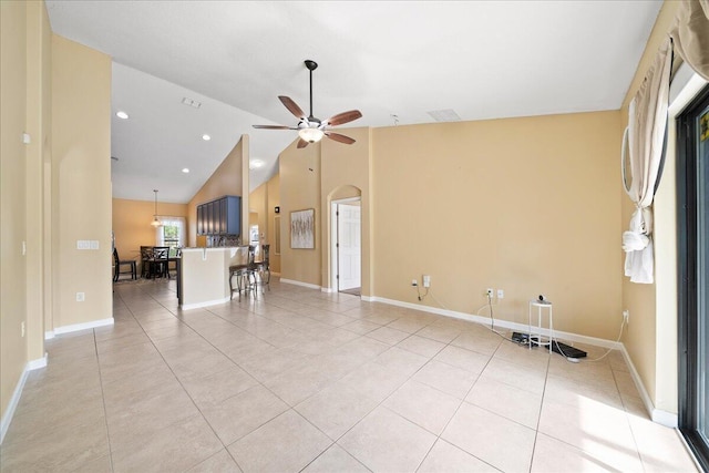 unfurnished living room featuring light tile patterned floors, baseboards, arched walkways, and ceiling fan