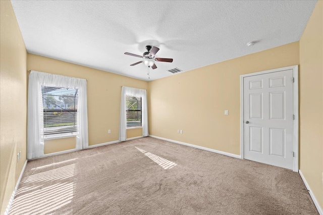 spare room featuring carpet flooring, baseboards, visible vents, and ceiling fan