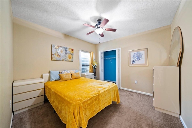 carpeted bedroom featuring a textured ceiling, a closet, baseboards, ceiling fan, and a spacious closet