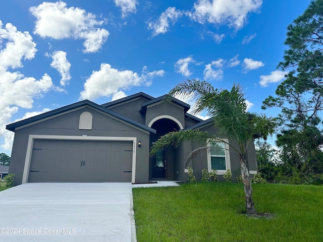 ranch-style home with an attached garage, driveway, a front yard, and stucco siding