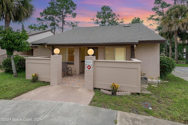 view of front of home featuring a patio area, roof with shingles, and stucco siding