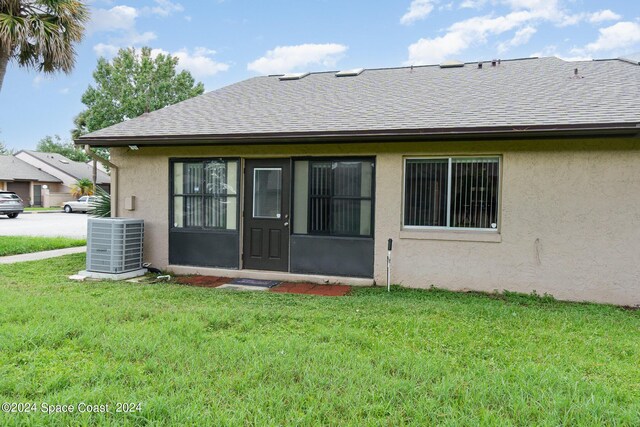 rear view of house with a yard and central AC