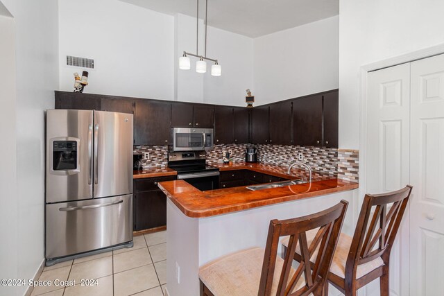 kitchen with a kitchen bar, kitchen peninsula, appliances with stainless steel finishes, and decorative backsplash