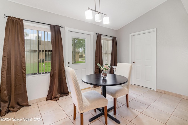 dining area featuring lofted ceiling, light tile patterned floors, baseboards, and an inviting chandelier