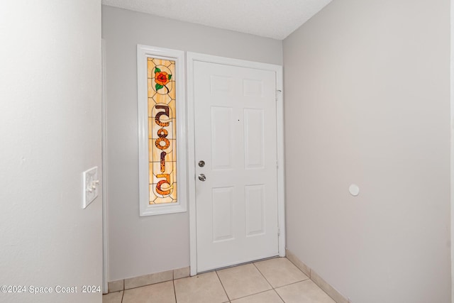 entryway featuring light tile patterned flooring, a textured ceiling, and baseboards