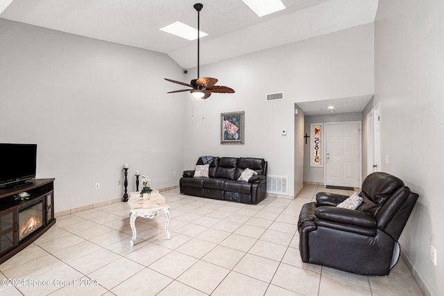 living room featuring a skylight, high vaulted ceiling, light tile patterned floors, and ceiling fan