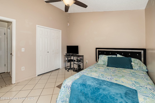 bedroom featuring a textured ceiling, vaulted ceiling, light tile patterned floors, a closet, and ceiling fan