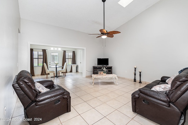 tiled living room featuring a skylight, high vaulted ceiling, and ceiling fan