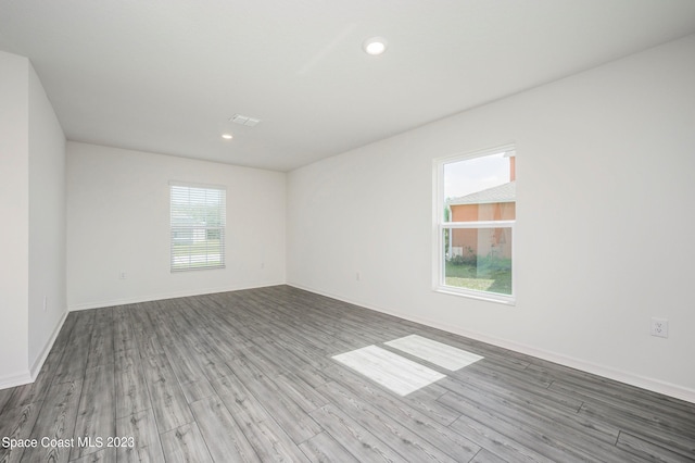 empty room with wood finished floors, baseboards, and recessed lighting