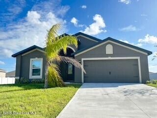single story home featuring an attached garage, concrete driveway, and a front lawn