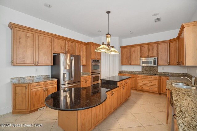 kitchen featuring dark stone countertops, pendant lighting, a center island, sink, and appliances with stainless steel finishes