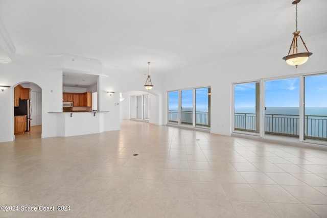 unfurnished living room featuring arched walkways and a water view