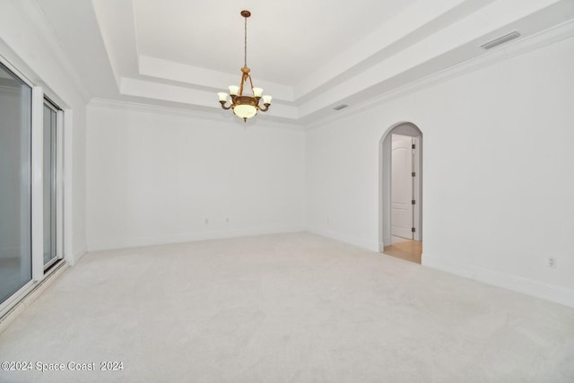 spare room with visible vents, baseboards, light carpet, arched walkways, and a raised ceiling