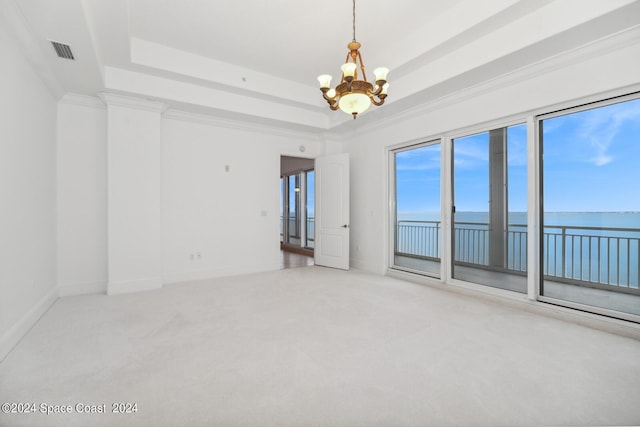 spare room featuring visible vents, carpet, a water view, ornamental molding, and a raised ceiling