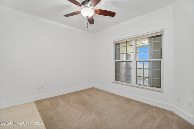 carpeted empty room with tile patterned floors, baseboards, and ceiling fan