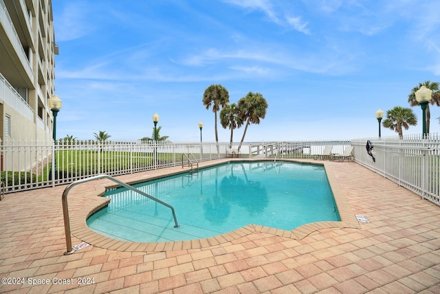 pool with a patio area and fence