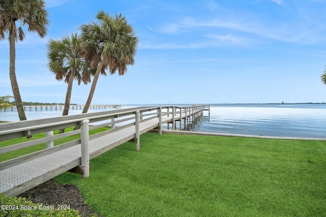 view of dock with a water view and a lawn