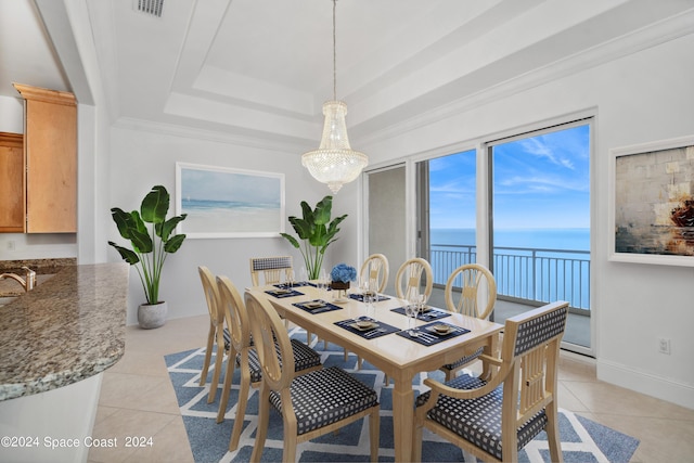 dining room featuring a raised ceiling, light tile patterned floors, visible vents, and a water view