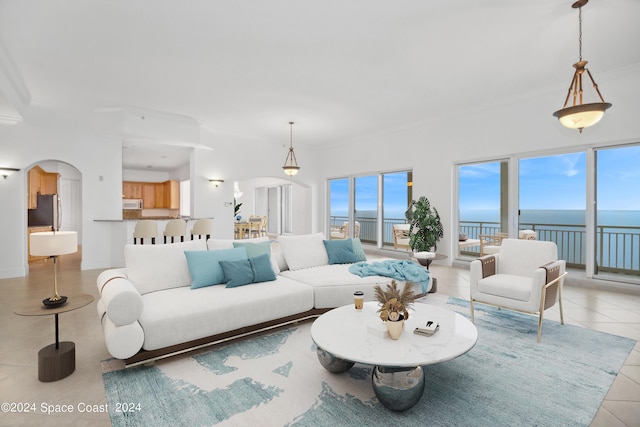 living room featuring tile patterned floors, arched walkways, a water view, and ornamental molding