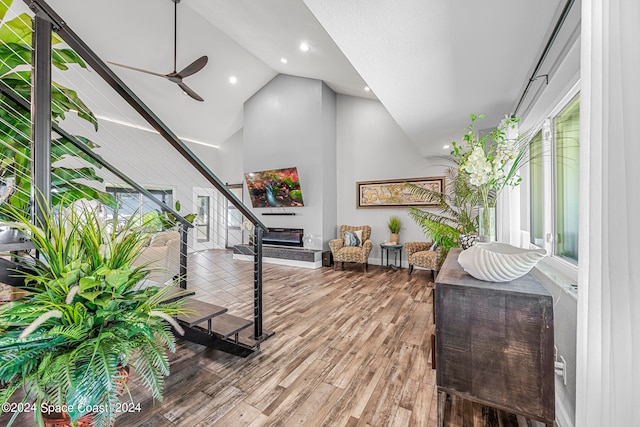 living room with plenty of natural light, high vaulted ceiling, wood-type flooring, and ceiling fan