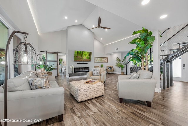 living room featuring a barn door, hardwood / wood-style floors, and high vaulted ceiling